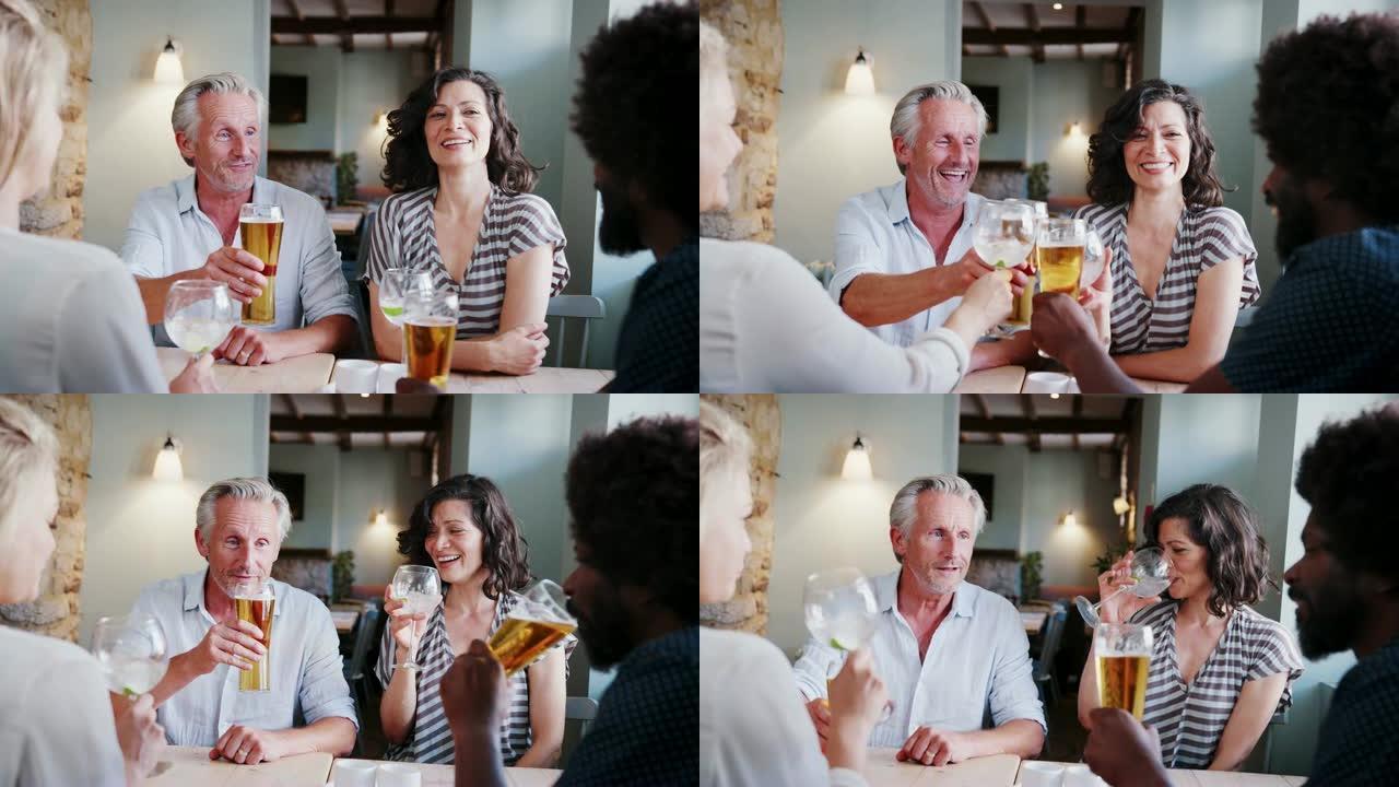 资深白人男子和西班牙裔妇女坐在酒吧的一张桌子旁，与同事敬酒，近距离观看
