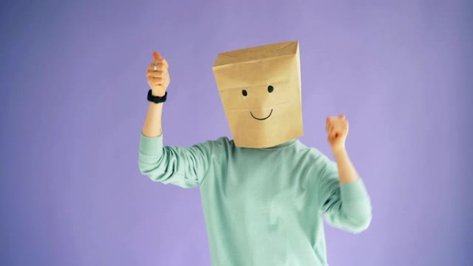 头上有纸袋的人显示竖起大拇指的手势和移动的身体跳舞