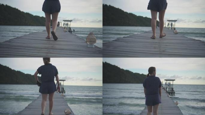 年轻女子在海边的木桥上行走