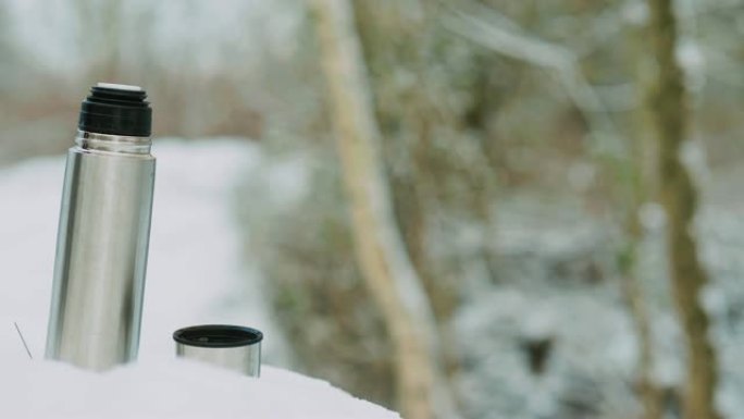在穿越森林的白雪皑皑的徒步旅行中喝咖啡休息