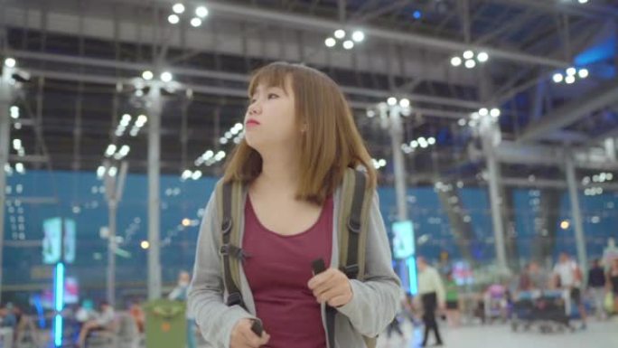 慢动作-年轻的亚洲背包客妇女在国际机场登机口登机时走在航站楼大厅。生活方式背包旅游度假概念。