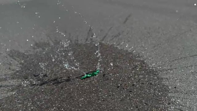 慢动作: 装满水的绿色气球落在沥青路面上并弹出。