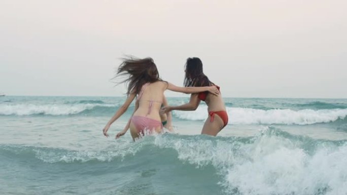 一群快乐的女孩朋友在海滩上玩水。暑假期间美丽的亚洲女孩。庆祝和放松的概念。