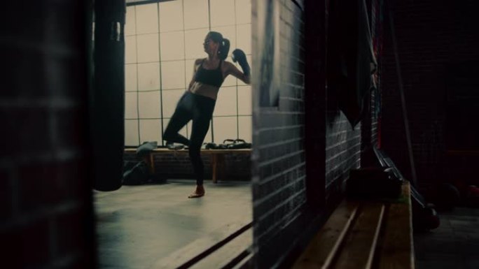 健身运动女性跆拳道运动员在阁楼健身房用激励海报锻炼时拳打脚踢。经过激烈的自卫训练，她筋疲力尽。照镜子
