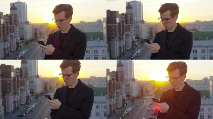 年轻人在日落时在屋顶上的智能手机上打字