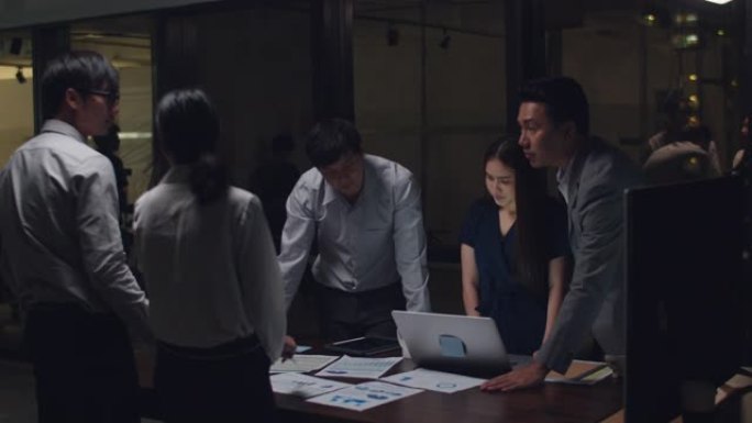 千禧一代亚洲商人会议关于新文书工作项目的头脑风暴想法同事一起工作规划成功战略享受在小型现代夜间办公室