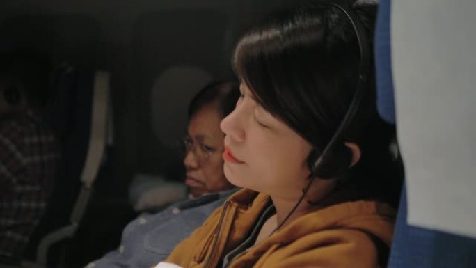 飞行中坐在座位上玩电子游戏的旅游妇女。