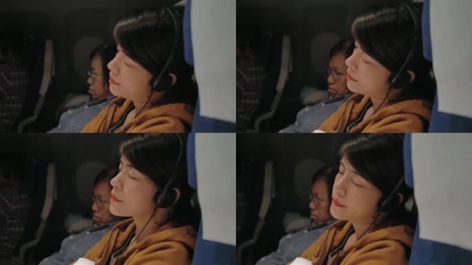 飞行中坐在座位上玩电子游戏的旅游妇女。