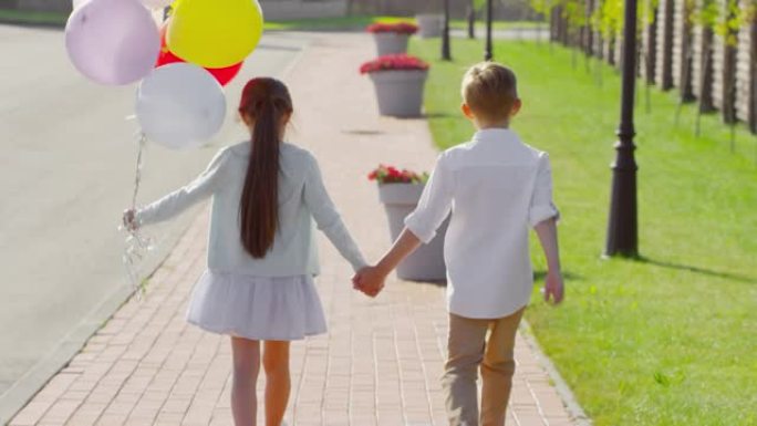 小哥哥小姐姐手牵着手，带着气球散步