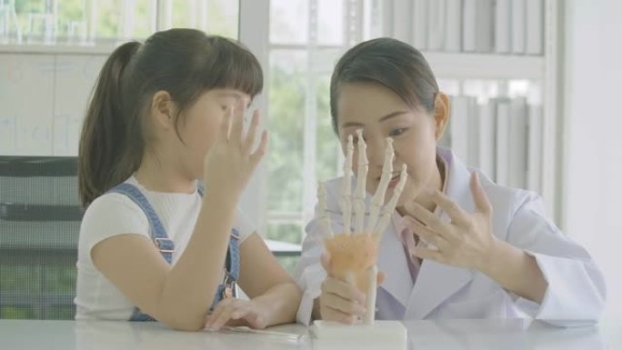 小亚洲学生女孩在解剖学课上学习人体骨骼。科学与教育。