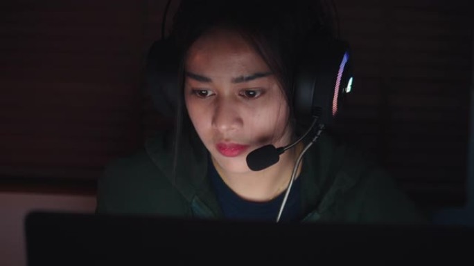 亚洲年轻女子晚上在笔记本电脑上玩网络游戏。