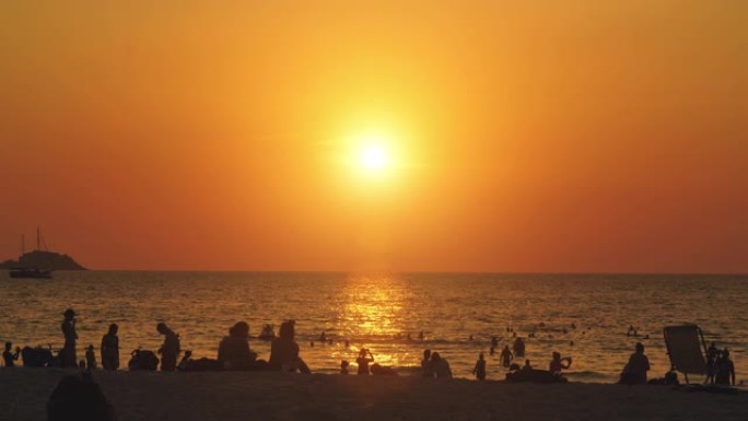 夏季日落时分，拥挤的人在海滩上享受