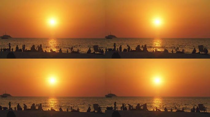 夏季日落时分，拥挤的人在海滩上享受