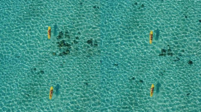 女人在黄色冲浪板上划水的鸟瞰图