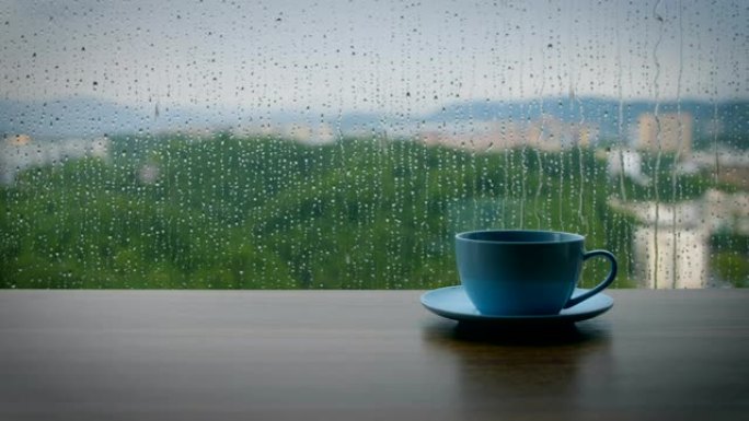 木制桌子上的咖啡杯，带有雨滴背景