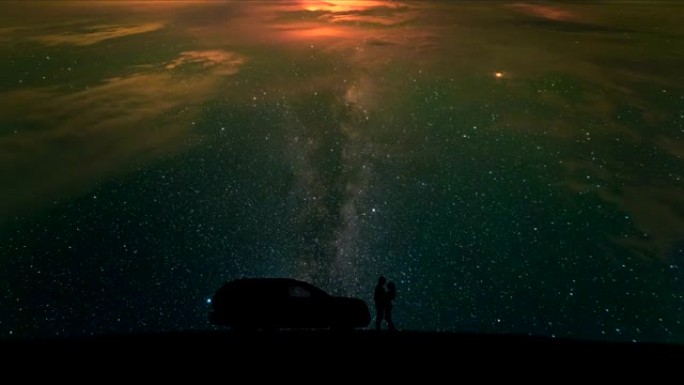 站在星空背景上的一辆汽车附近的男人和女人。时间流逝