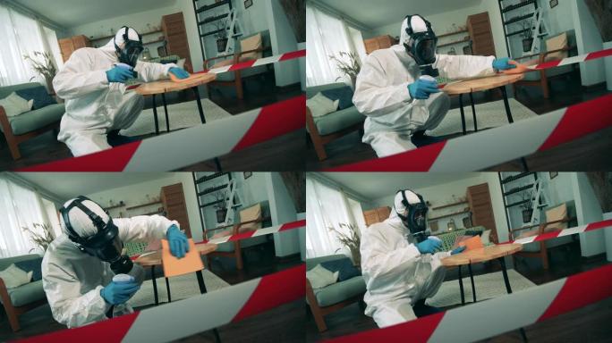 一个穿着危险品套装的人正在打扫公寓里的桌子。新型冠状病毒肺炎大流行期间的消毒过程。