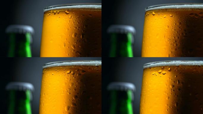 湿旋转杯淡啤酒和一个绿色啤酒瓶的顶部。黑色和灰色背景。UHD