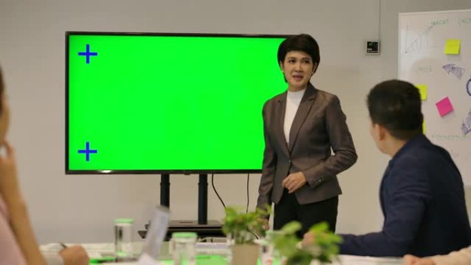 商业演示。有吸引力的女商人在会议室的绿屏显示器前向同事展示。