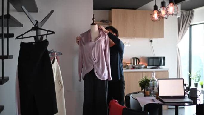 一位亚洲中国中年妇女在她的饭厅里设置人体模型并用布打扮成网上购物业务目录
