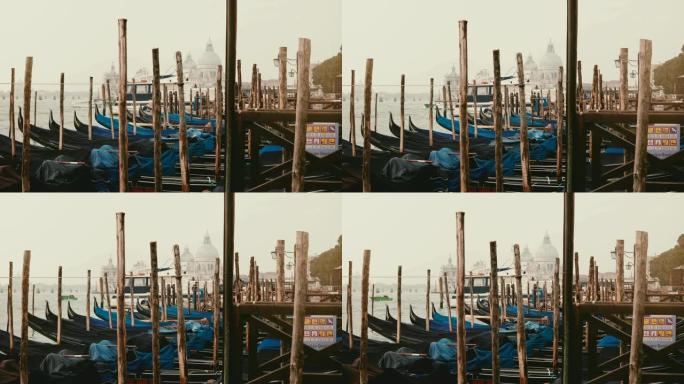 传统的意大利吊船在意大利威尼斯雾蒙蒙的木制码头上摇曳，背景是旧建筑