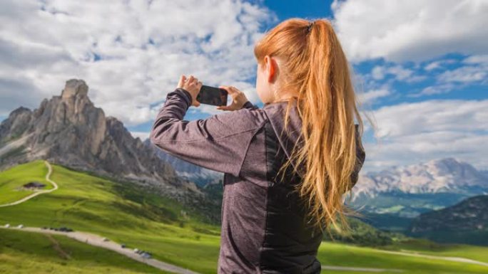 女游客用智能手机拍摄山景全景照片