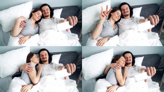 大胡子的家伙用智能手机相机和女朋友在床上自拍