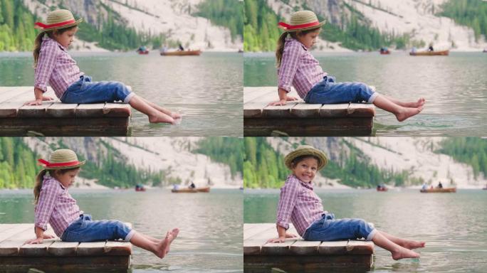 湖边码头上的一个小女孩玩一艘纸船，让她冲浪和吹风，让她旅行。
