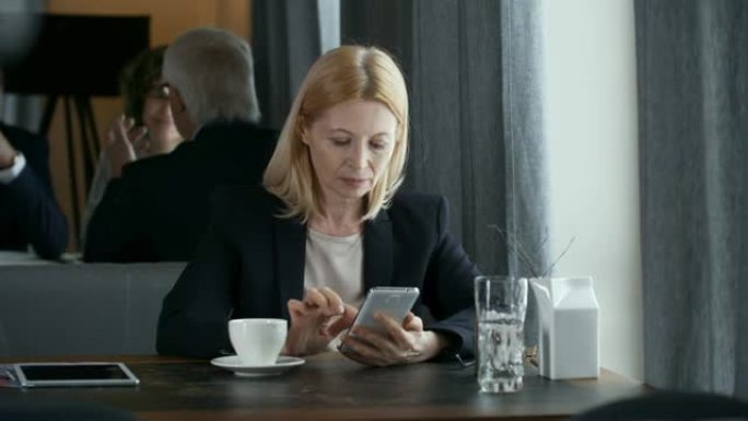 在餐厅使用智能手机的高级女商人