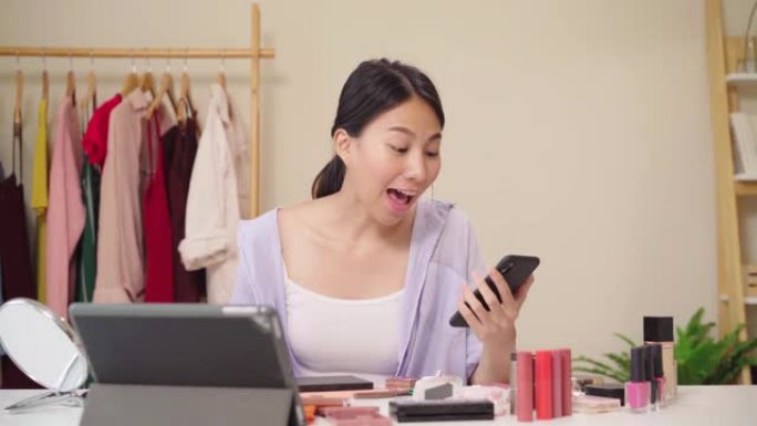 美容博主问答坐在平板电脑前录制视频的电话。快乐美丽的年轻亚洲女人使用化妆品评论化妆教程直播视频到社交