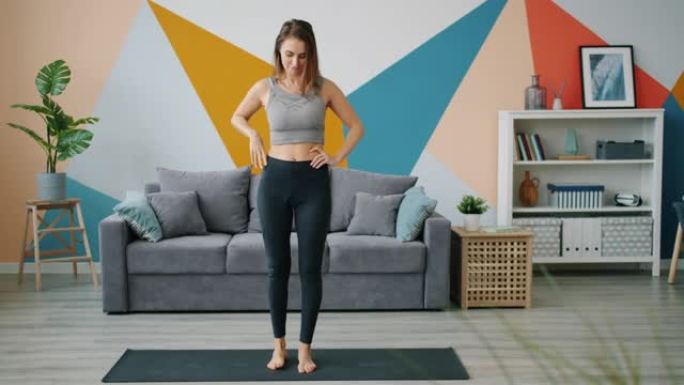 穿着紧身裤和单腿顶部平衡的漂亮女人在家练习瑜伽