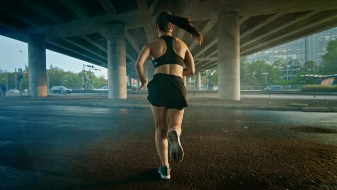 一个穿着黑色运动上衣和短裤的强壮健身女孩在烟熏街道上慢跑的背景。她在城市环境中奔跑，背景是汽车。