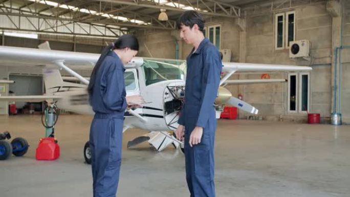 跟随两名亚洲工程师在机库飞机上交谈并寻找解决方案维护时走过飞机维护的镜头。STEM概念中的女性。