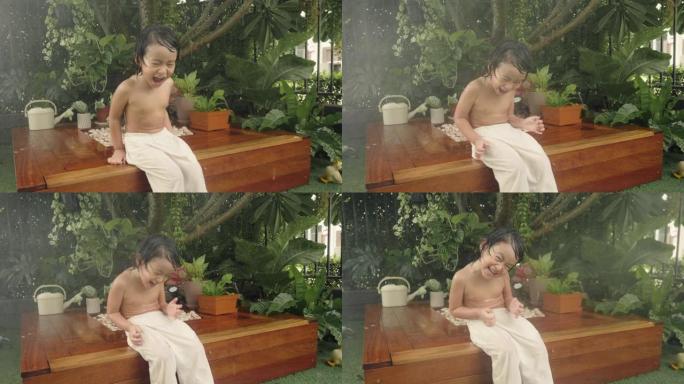 亚洲宝宝在家前院微笑着玩水。
