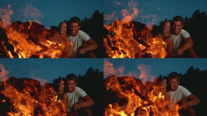 慢动作: 快乐的女人在火旁拥抱男友时笑。