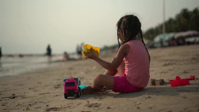 女孩在海滩玩沙子和玩具
