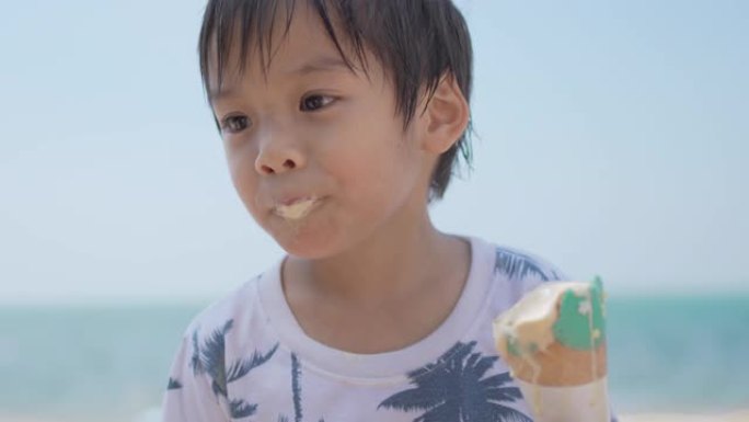 快乐的小男孩在海边的海滩上吃冰淇淋