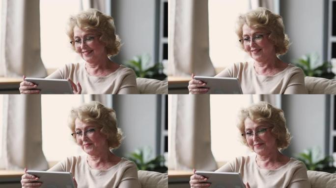 微笑的高级女士戴着光学眼镜，使用平板电脑和家庭。
