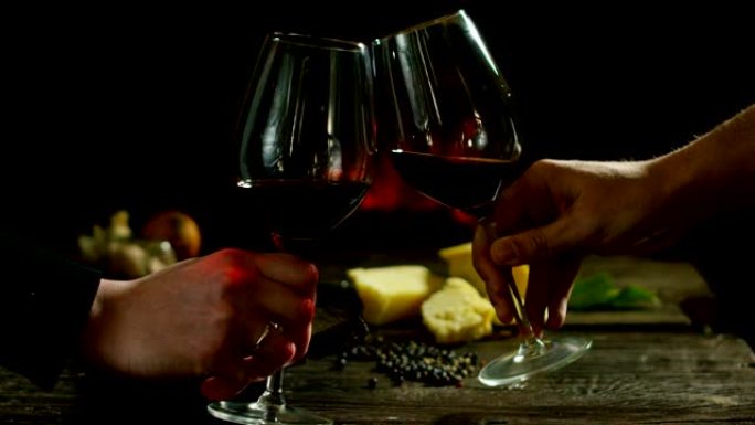 女人和男人的手在古老的传统小屋里用美丽的意大利红酒欢呼，壁炉和放松的氛围