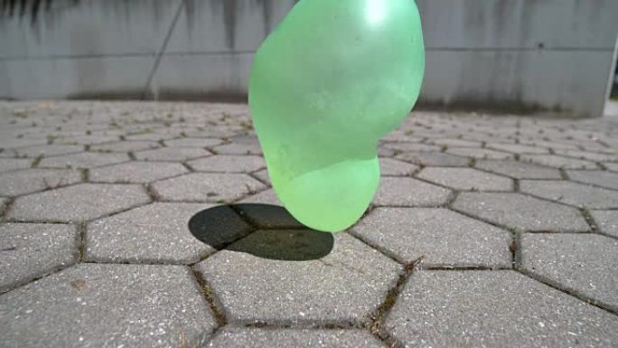 特写: 绿色橡胶气球落在瓷砖地面上后不会弹出。