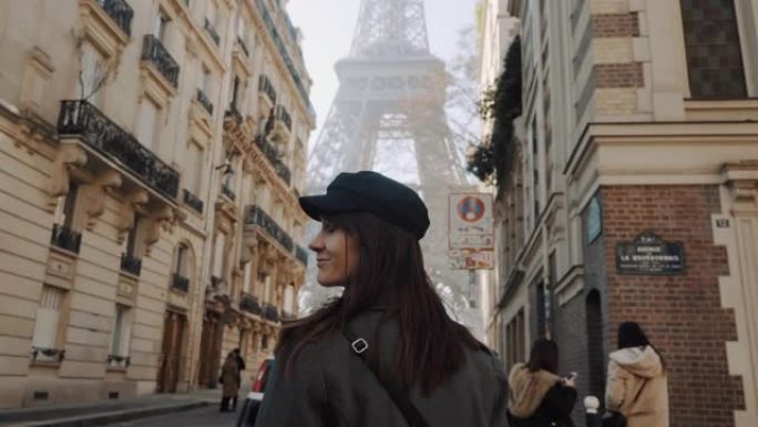 摄像机跟随快乐美丽微笑的旅游女人在浪漫的巴黎度假慢动作中走向埃菲尔铁塔广场。