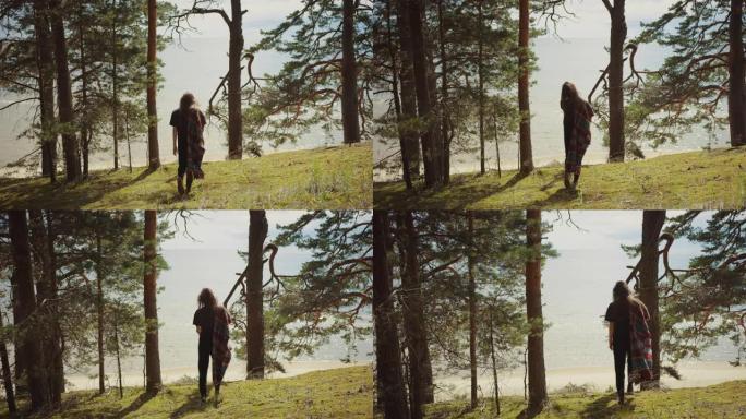 穿着黑色衣服的年轻女子在欧洲松树林中散步。这是大自然温暖的晴天。她来到边缘，看着海景。