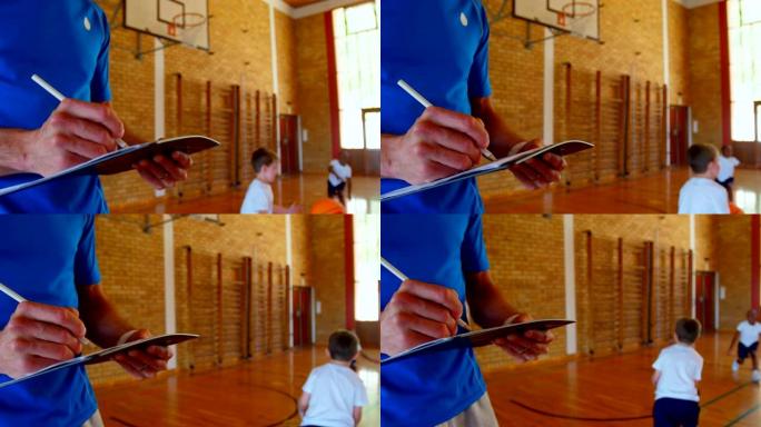 篮球教练在学校4k的篮球场上的记事本上写字