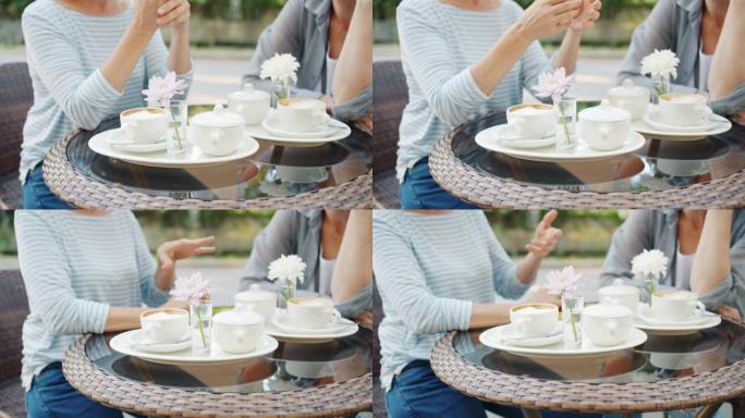 匿名妇女坐在街头咖啡馆的桌子旁打手势，专注于饮料