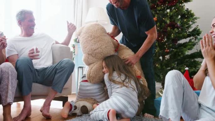 孩子们在圣诞节那天玩巨型泰迪熊作为多代家庭开放礼物