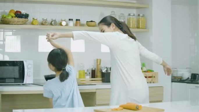 孕妇和女儿在家做饭跳舞。家庭、食物、家庭和人的概念。