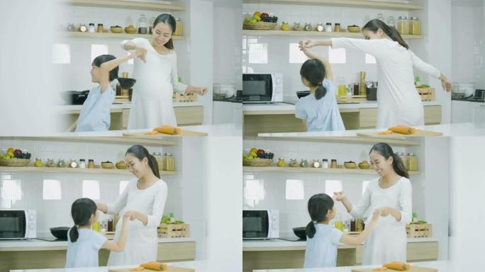 孕妇和女儿在家做饭跳舞。家庭、食物、家庭和人的概念。
