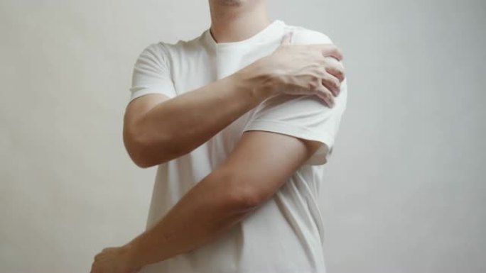 穿着白衬衫的亚洲男人感到肩膀疼痛。肌肉疼痛，保健概念。