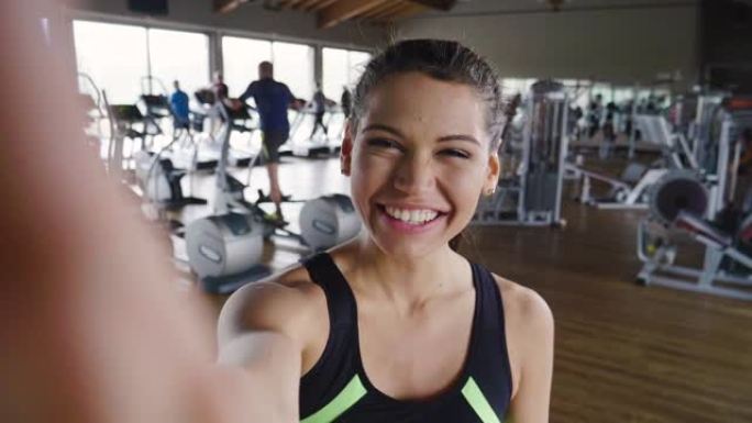 健身房里的女人拍照发送给朋友或在社交网络上拍照，并在微笑时拍照。