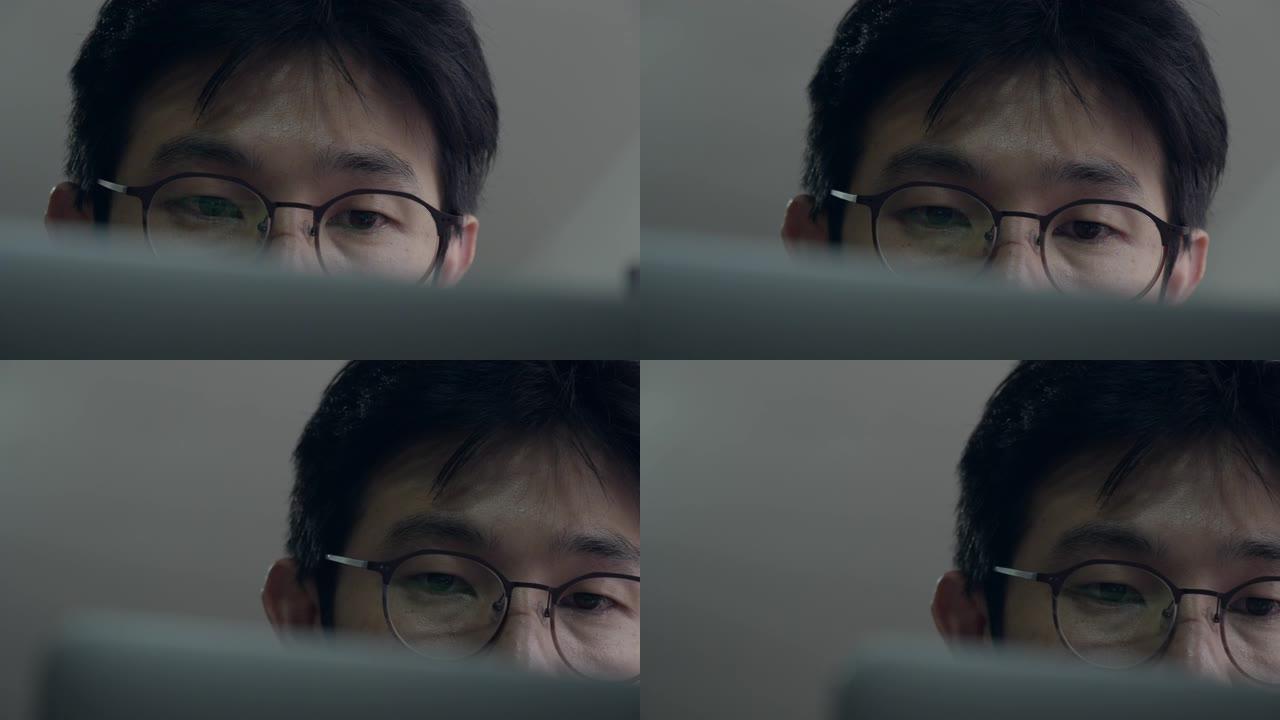 亚洲男子通过在家中的笔记本电脑屏幕上学习班级